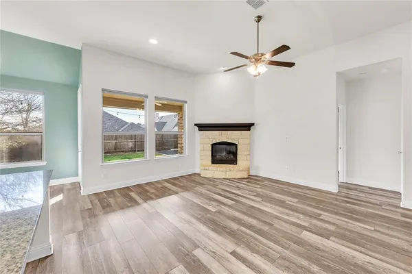 a view of a livingroom with a fireplace a ceiling fan and wooden floor