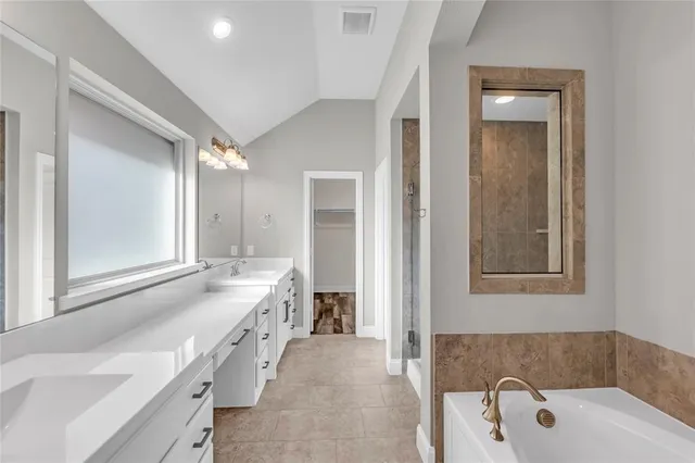 a bathroom with a tub a sink and mirror