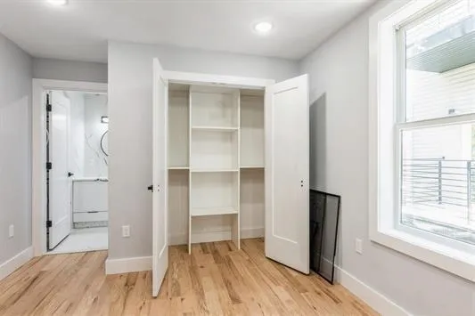 a view of walk in closet with window and wooden floor