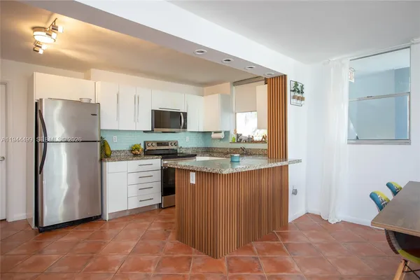 a kitchen with stainless steel appliances granite countertop a refrigerator a stove a sink a microwave and a refrigerator