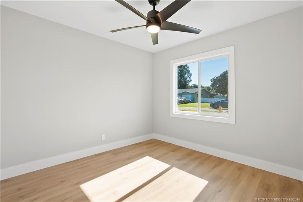 3023 Southeast Banyan Street Stuart, FL 34997 - Photo 18 of 24 an empty room with wooden floor chandelier fan and windows
