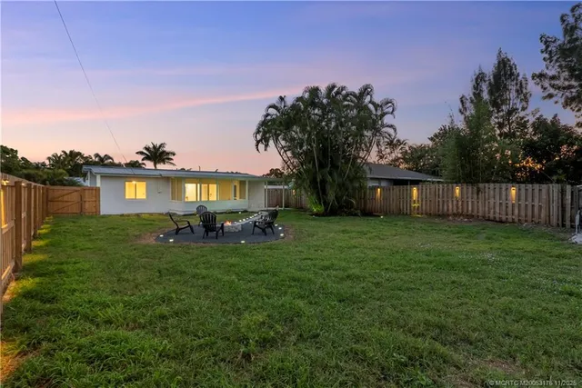 a view of a house with a yard fire pit and a large tree