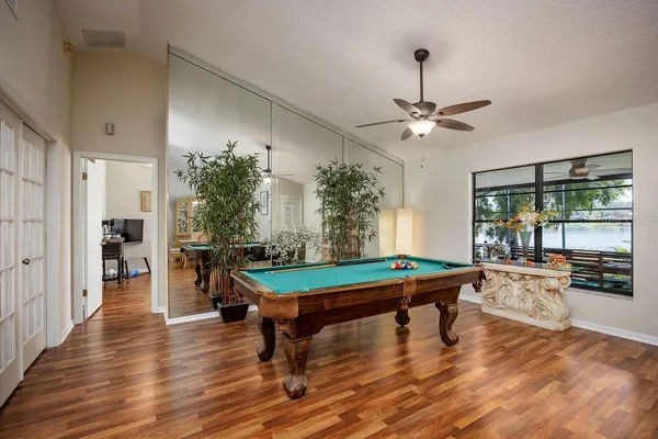 a room with pool table windows and wooden floor
