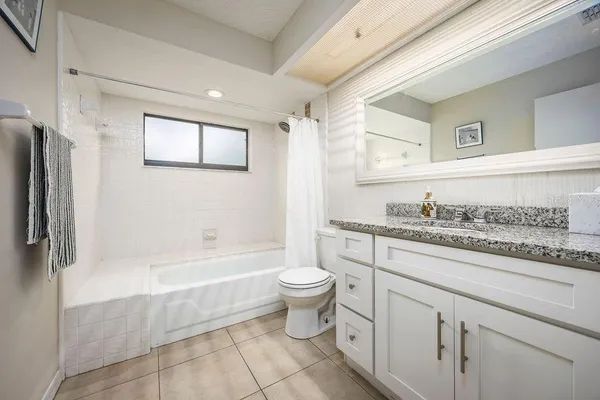 a bathroom with a granite countertop toilet sink and mirror