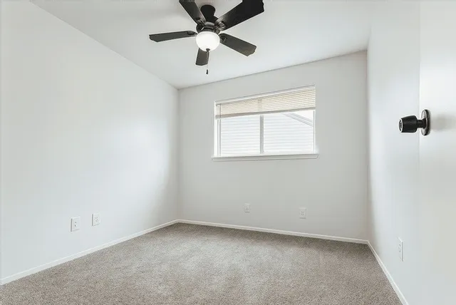 an empty room with a window and a fan