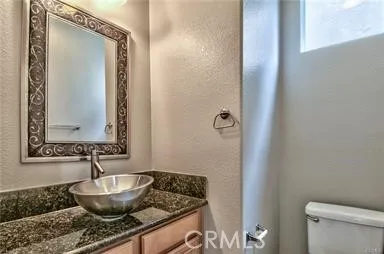 a bathroom with a granite countertop sink and a toilet