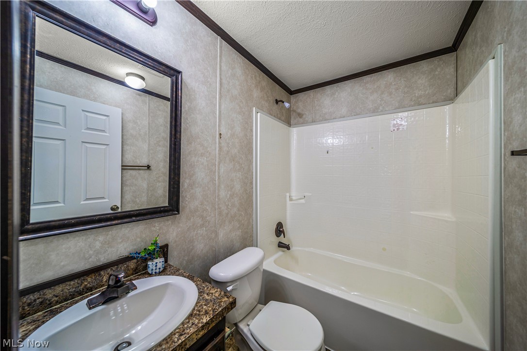 3651 Austin Road, Unit N28 Geneva, OH 44041 - Photo 24 of 30 Full bathroom with washtub / shower combination, vanity with extensive cabinet space, toilet, and a textured ceiling