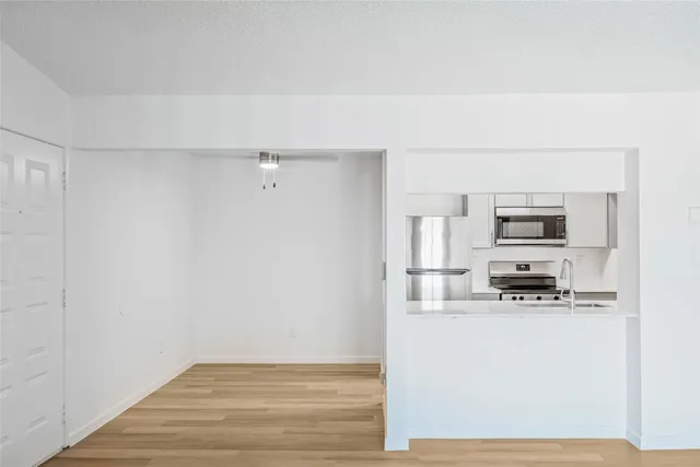 a view of an empty room with wooden floor and windows