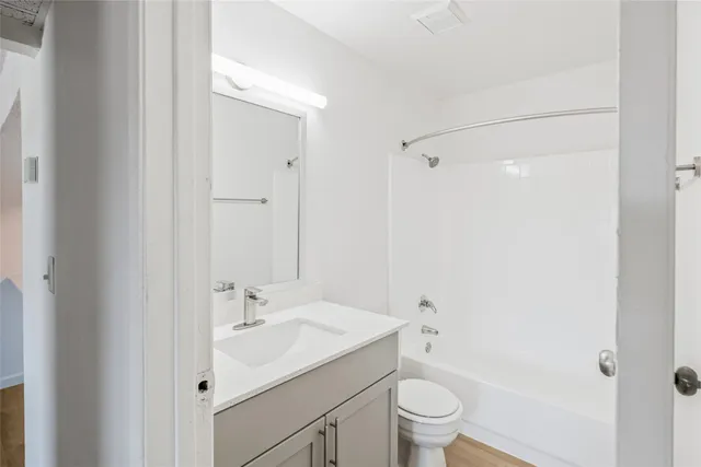 a bathroom with a bathtub shower sink vanity mirror and toilet