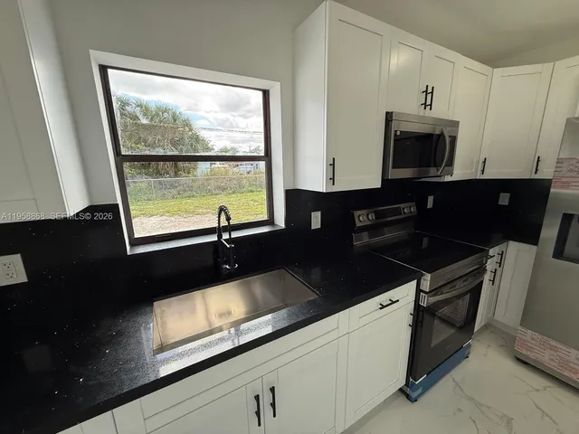 a kitchen with stainless steel appliances a refrigerator sink stove microwave and cabinets