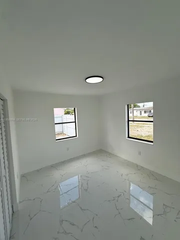 an empty room with windows and cabinet