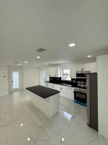 a kitchen with stainless steel appliances a sink a stove a microwave and a refrigerator