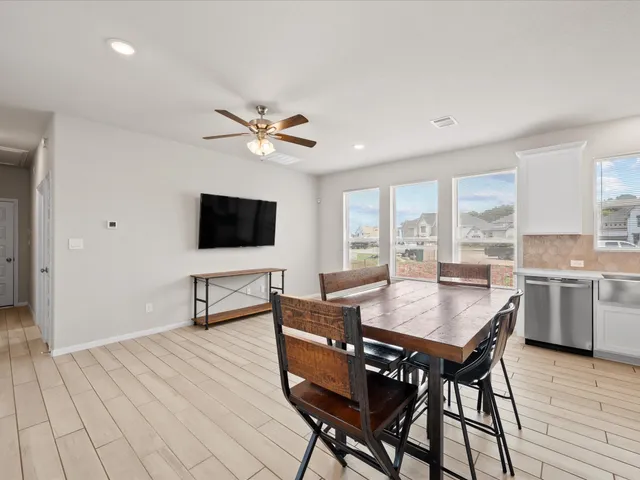 a open kitchen with stainless steel appliances granite countertop a stove top oven a refrigerator a dining table and chairs with wooden floor