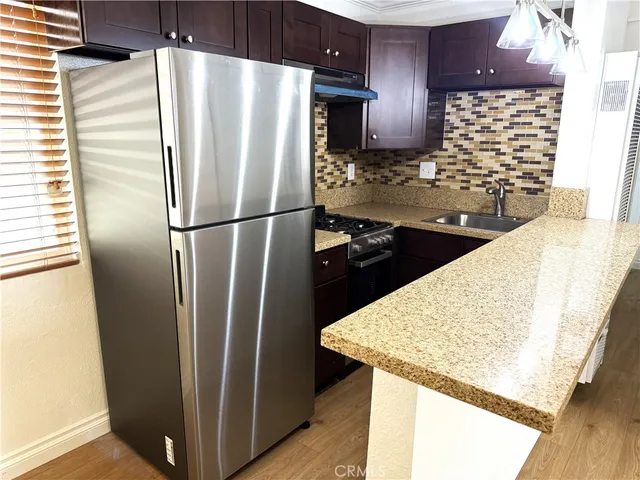 a view of a kitchen with wooden floor and a refrigerator