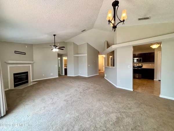 a view of a livingroom with a fireplace a chandelier and stairs