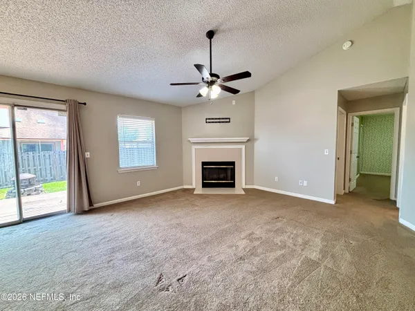 a view of an empty room with a fireplace and a window
