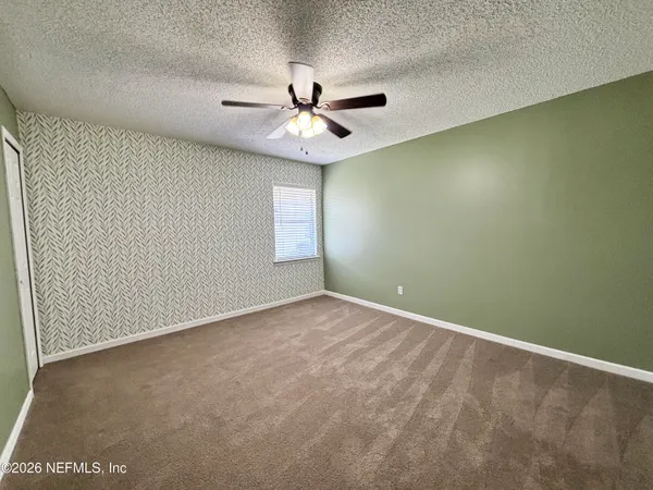 an empty room with windows and fan