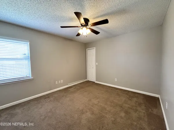 an empty room with window and ceiling fan