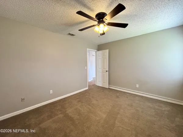 an empty room with a chandelier fan and a window
