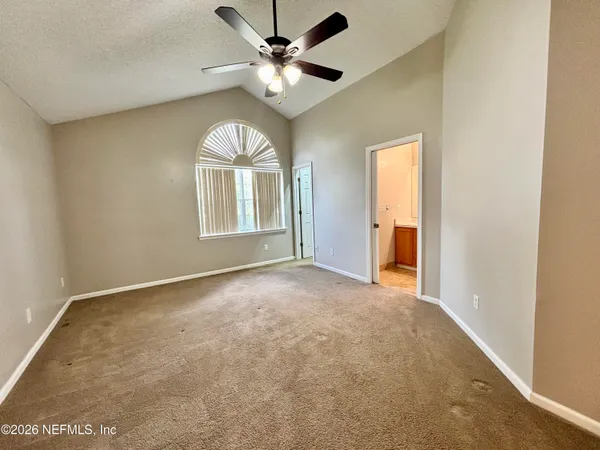 an empty room with a chandelier fan and windows