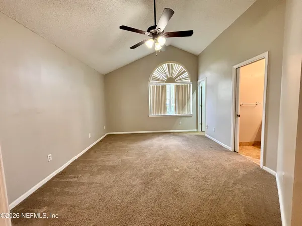 an empty room with windows and ceiling fan