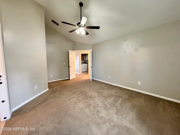an empty room with chandelier fan and windows