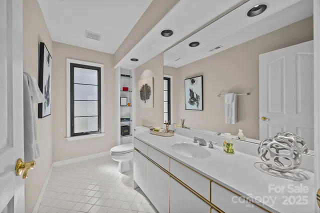a bathroom with a granite countertop sink mirror vanity and toilet