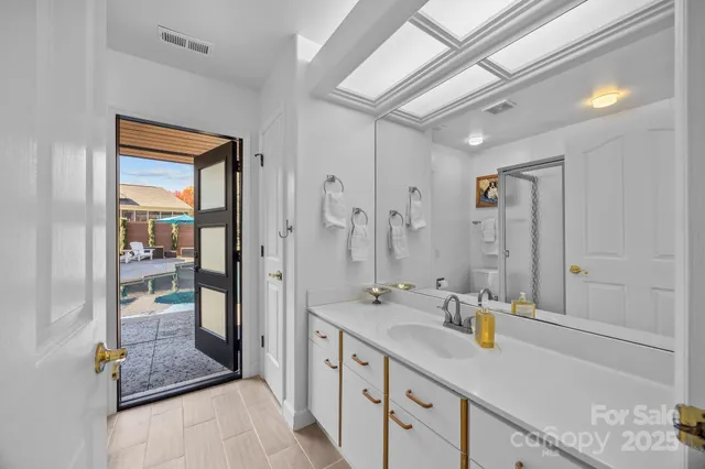 a bathroom with a granite countertop sink a mirror and shower