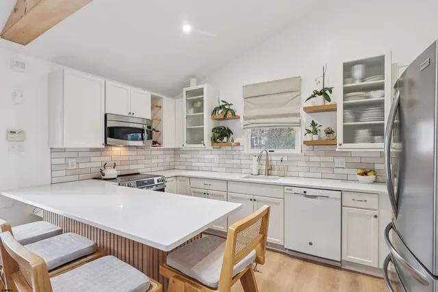 a kitchen with a sink a stove a refrigerator and white cabinets