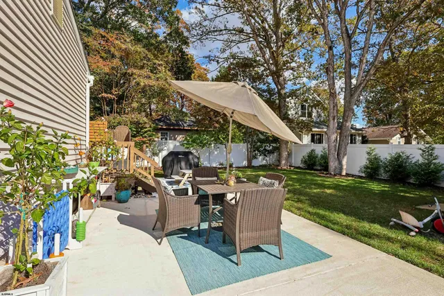 a view of a patio with table and chairs potted plants and a large tree