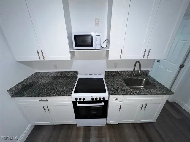 a kitchen with granite countertop white cabinets and white appliances