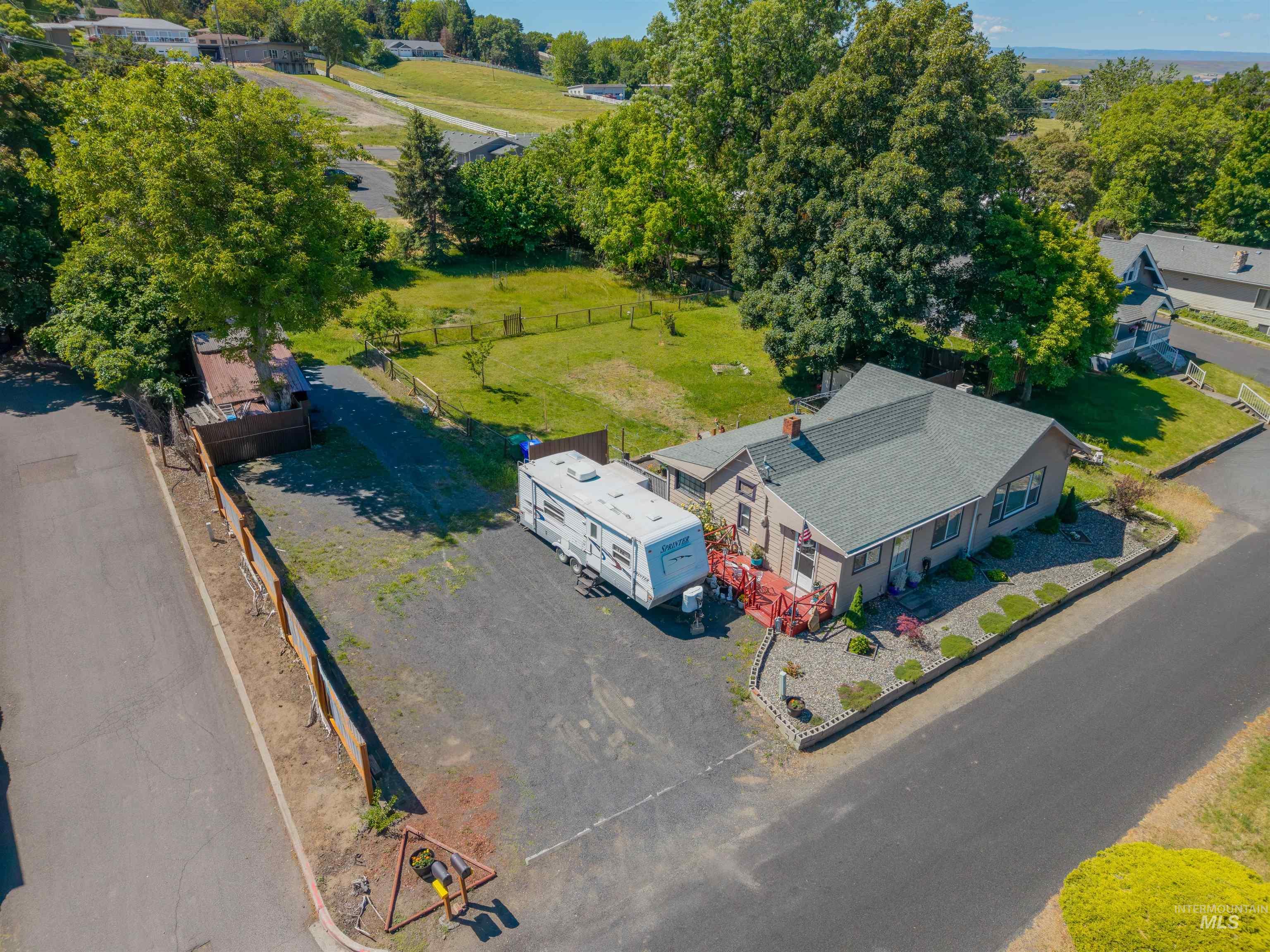 238 Hillcrest Road Lewiston, ID 83501 - Photo 7 of 27 Expansive paved lot with a single-story residence featuring a red-painted deck