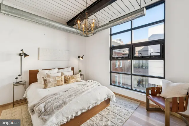 a bedroom with a bed a table and a large window