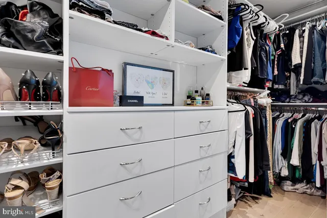 a view of walk in closet with clothes and shoes