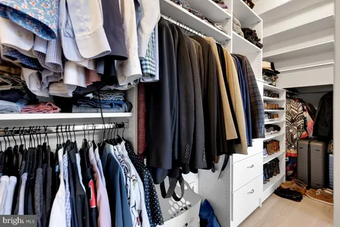 a view of walk in closet with clothes and shoes