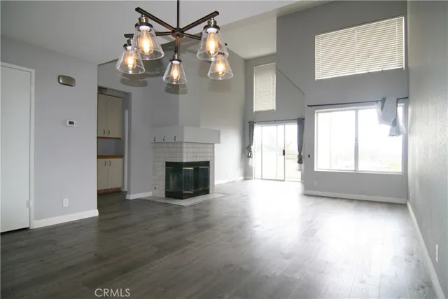 an empty room with wooden floor fireplace and windows