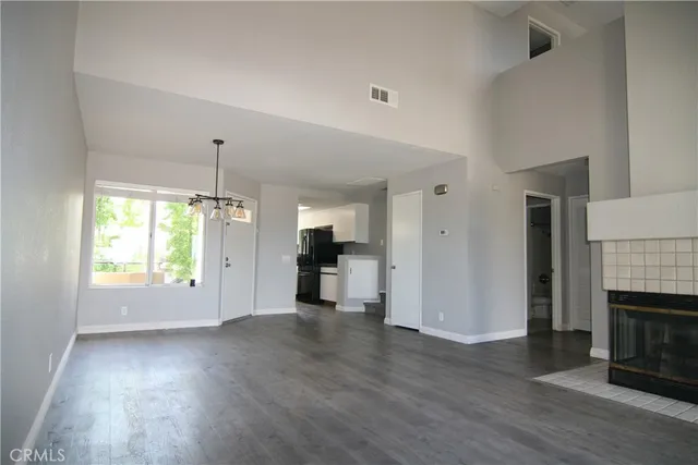 an empty room with wooden floor fireplace and windows