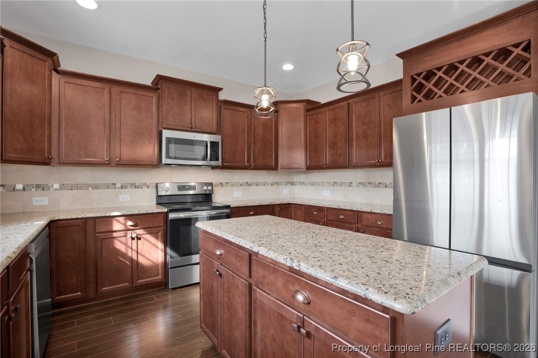 171 Tellmont Street Raeford, NC 28376 - Photo 18 of 46 a kitchen with granite countertop wooden cabinets a stove a sink and a oven with wooden floor
