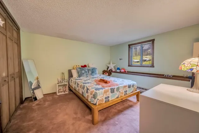 a bedroom with a bed and a dresser next to a window