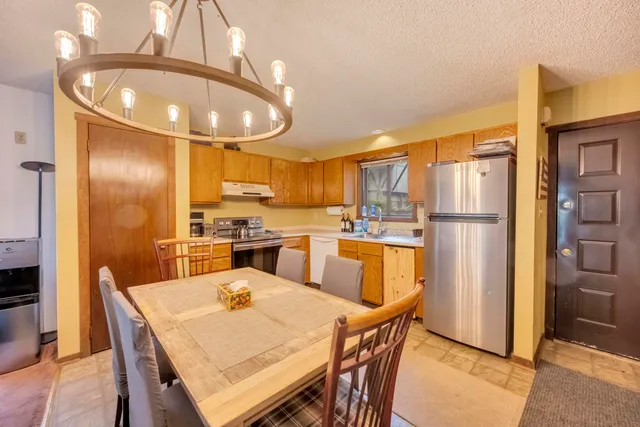 a kitchen with stainless steel appliances kitchen island granite countertop a refrigerator a stove a kitchen island with a dining table and chairs