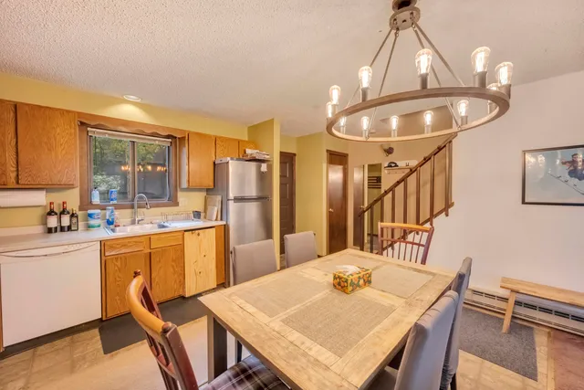 a kitchen with stainless steel appliances granite countertop a sink a stove a refrigerator a dining table and chairs with wooden floor