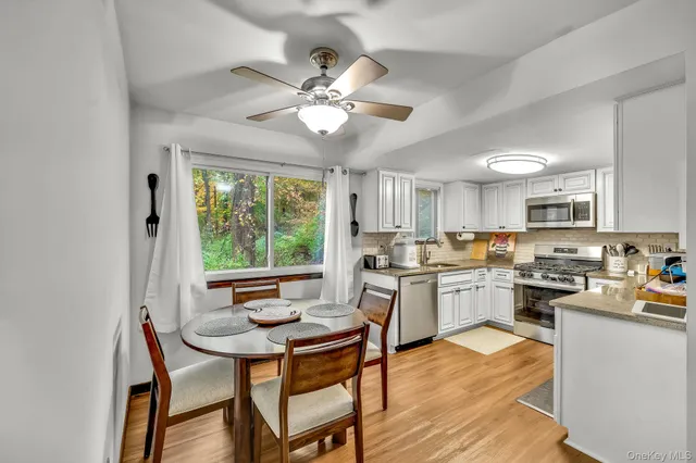 a kitchen with stainless steel appliances granite countertop a stove top oven a sink dishwasher and white cabinets with wooden floor