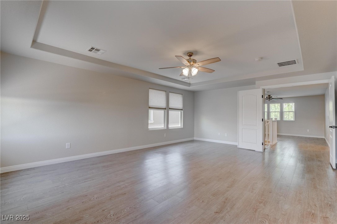 10273 Aragon Crown Road Las Vegas, NV 89135 - Photo 10 of 45 Spare room featuring a raised ceiling, ceiling fan, and light wood-type flooring