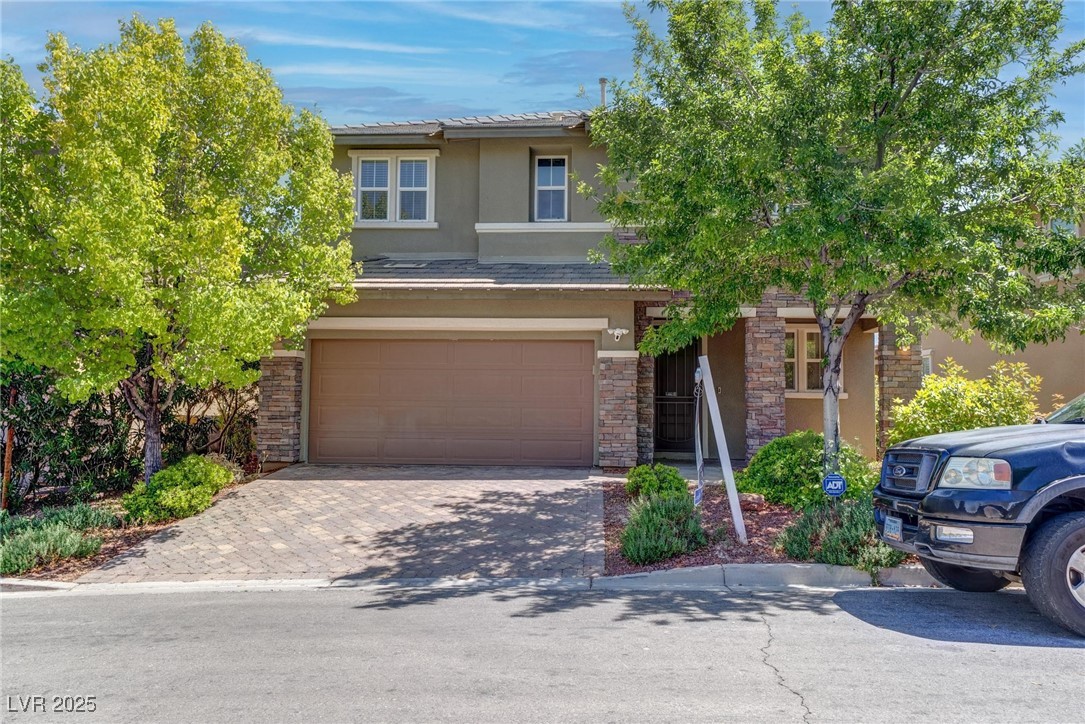 10273 Aragon Crown Road Las Vegas, NV 89135 - Photo 2 of 45 View of front of property with stucco siding, decorative driveway, an attached garage, and stone siding