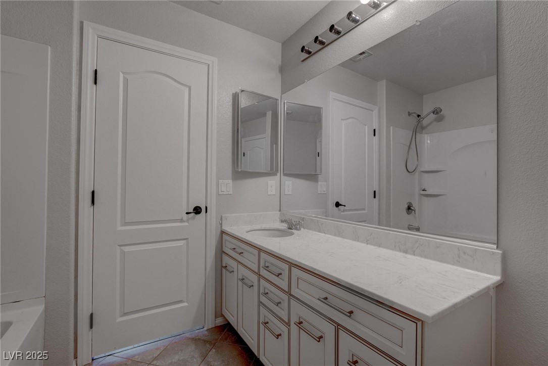 10273 Aragon Crown Road Las Vegas, NV 89135 - Photo 21 of 45 Full bath with vanity, shower / bathtub combination, light tile patterned flooring, and a textured wall