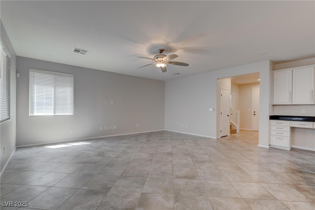10273 Aragon Crown Road Las Vegas, NV 89135 - Photo 27 of 45 Unfurnished living room with built in study area, ceiling fan, and light tile patterned floors