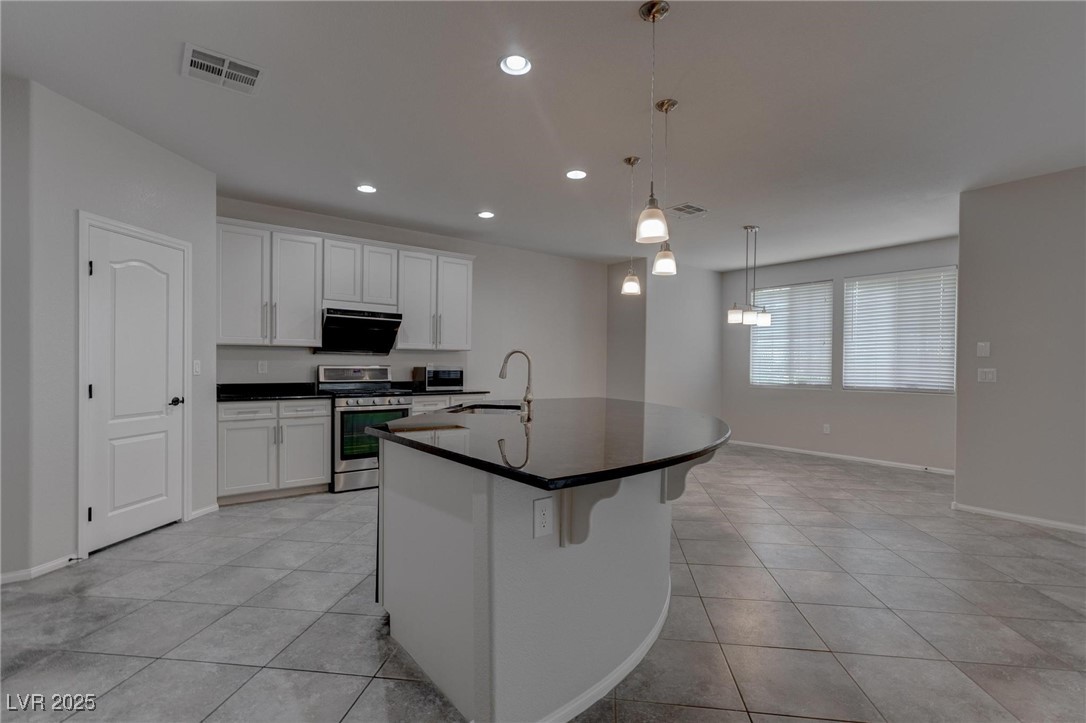 10273 Aragon Crown Road Las Vegas, NV 89135 - Photo 29 of 45 Kitchen featuring stainless steel range with gas stovetop, an island with sink, white cabinets, pendant lighting, and recessed lighting