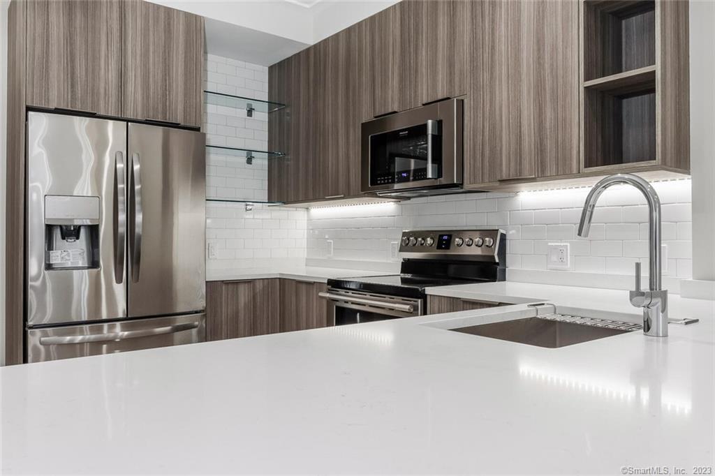 1990 Bronson Road, Unit 8 Fairfield, CT 06824 - Photo 14 of 28 a kitchen with granite countertop a refrigerator and a sink