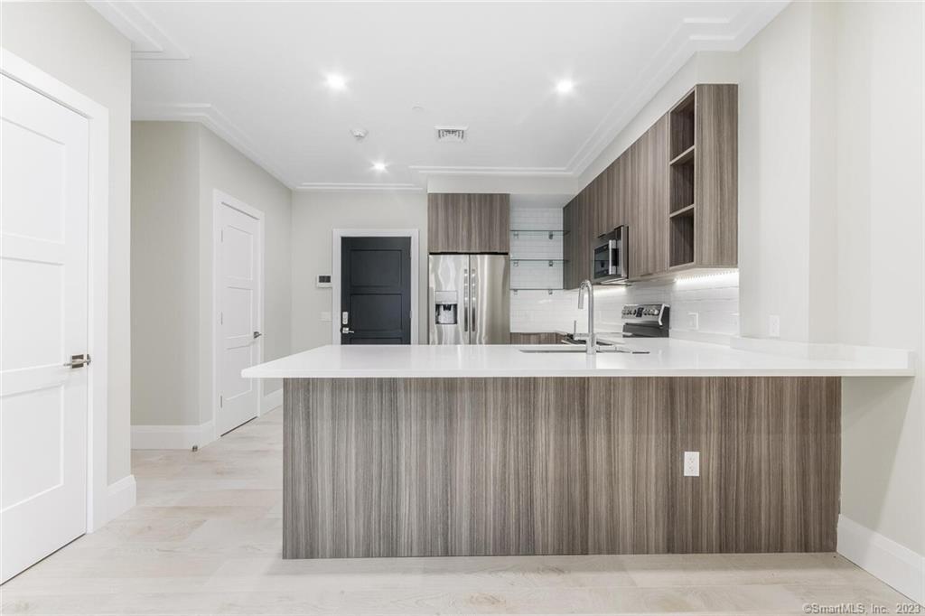 1990 Bronson Road, Unit 8 Fairfield, CT 06824 - Photo 8 of 28 a kitchen with kitchen island a sink stainless steel appliances and cabinets