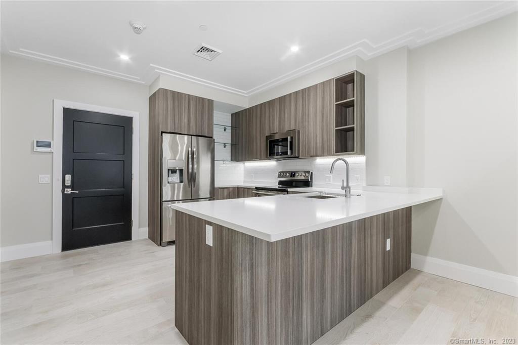 1990 Bronson Road, Unit 8 Fairfield, CT 06824 - Photo 10 of 28 a kitchen with kitchen island a refrigerator sink and microwave